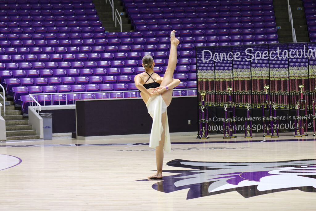 A ballet dancer performing an elegant arabesque in a dance studio.
