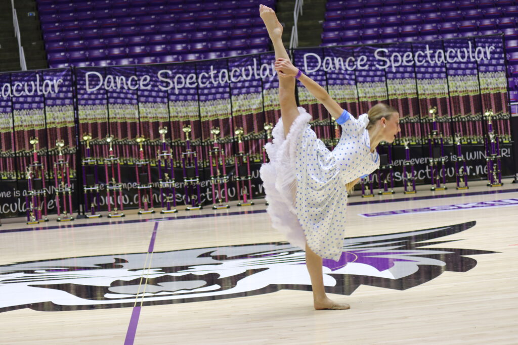 Young girl performs a graceful dance pose at a competition.